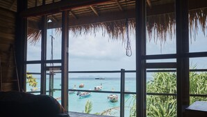 A room with a large window overlooking a turquoise sea with boats. - Castaway Resort Koh Lipe (Koh Lipe)