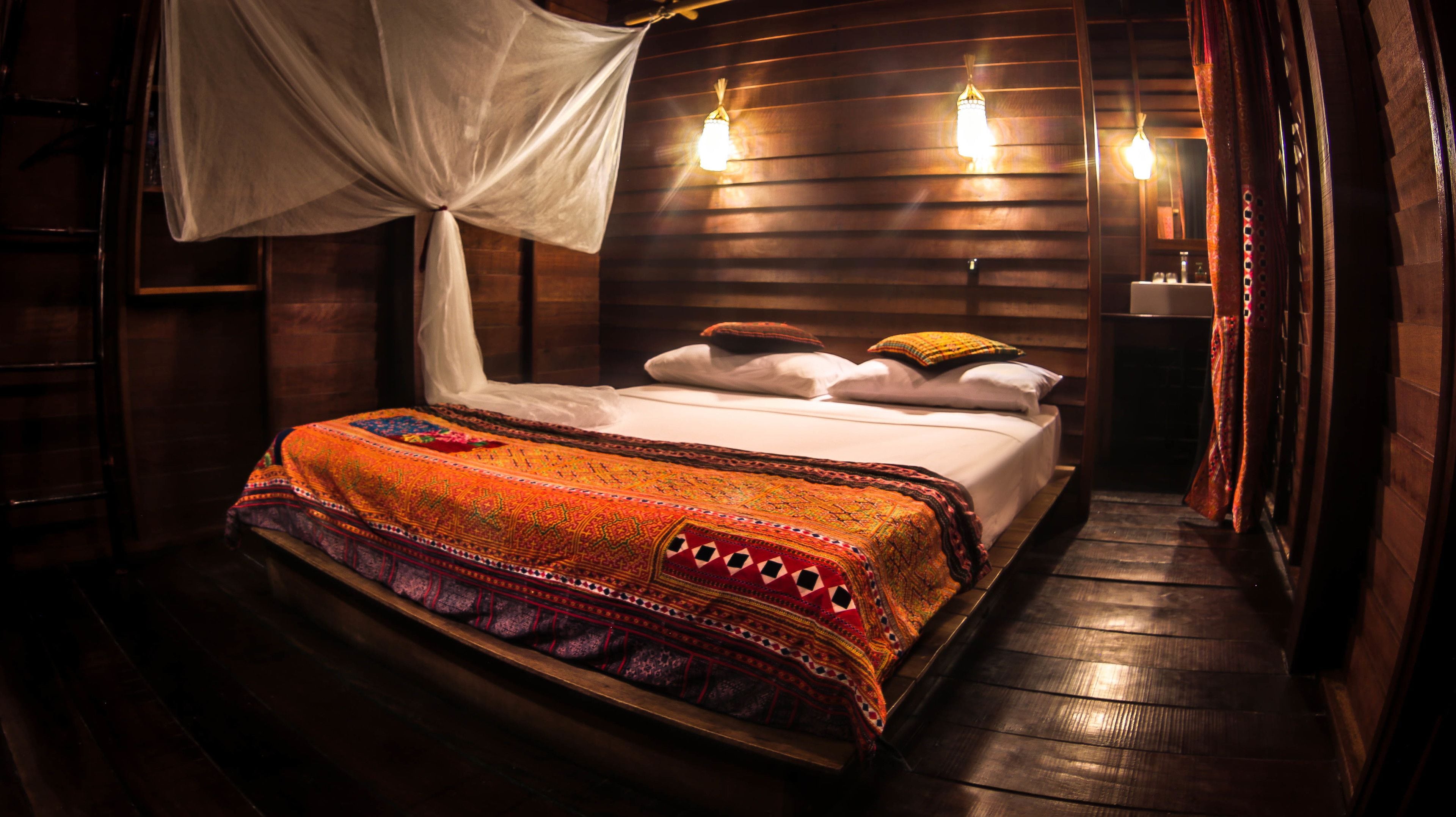 Une chambre avec un lit, un baldaquin et une table de chevet avec une lampe.