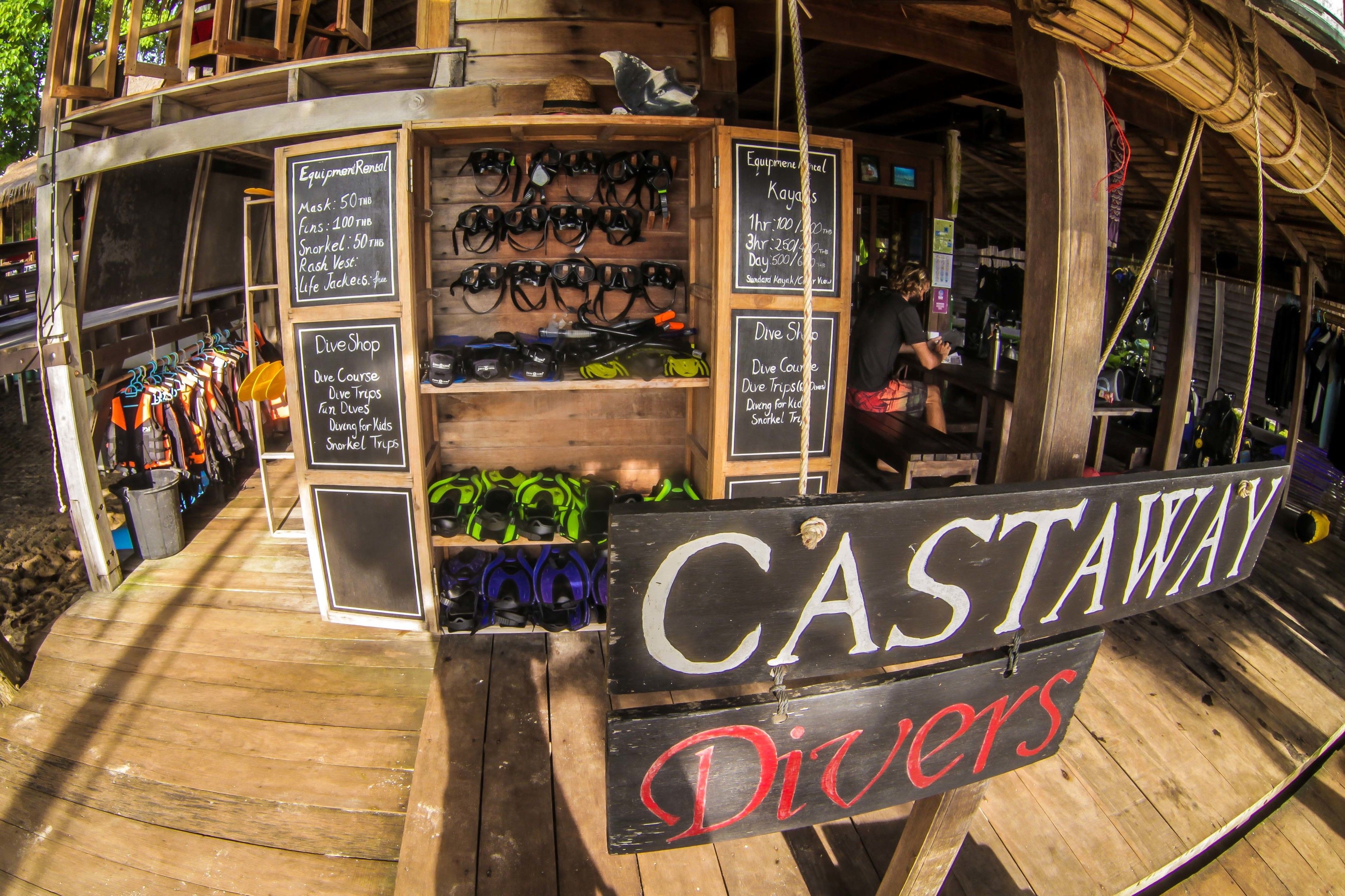 A wooden structure with a sign reading "CASTAWAY Divers" and various diving equipment displayed on shelves.
