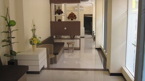 A modern interior with a sofa, a small table, and a potted plant. - Lily Guest House (Malang)