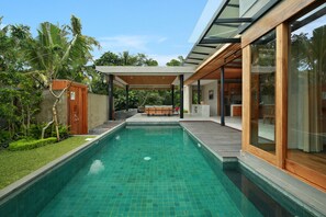 A modern house with a swimming pool, wooden deck, and large glass windows. - Sativa Villas Ubud (Ubud)