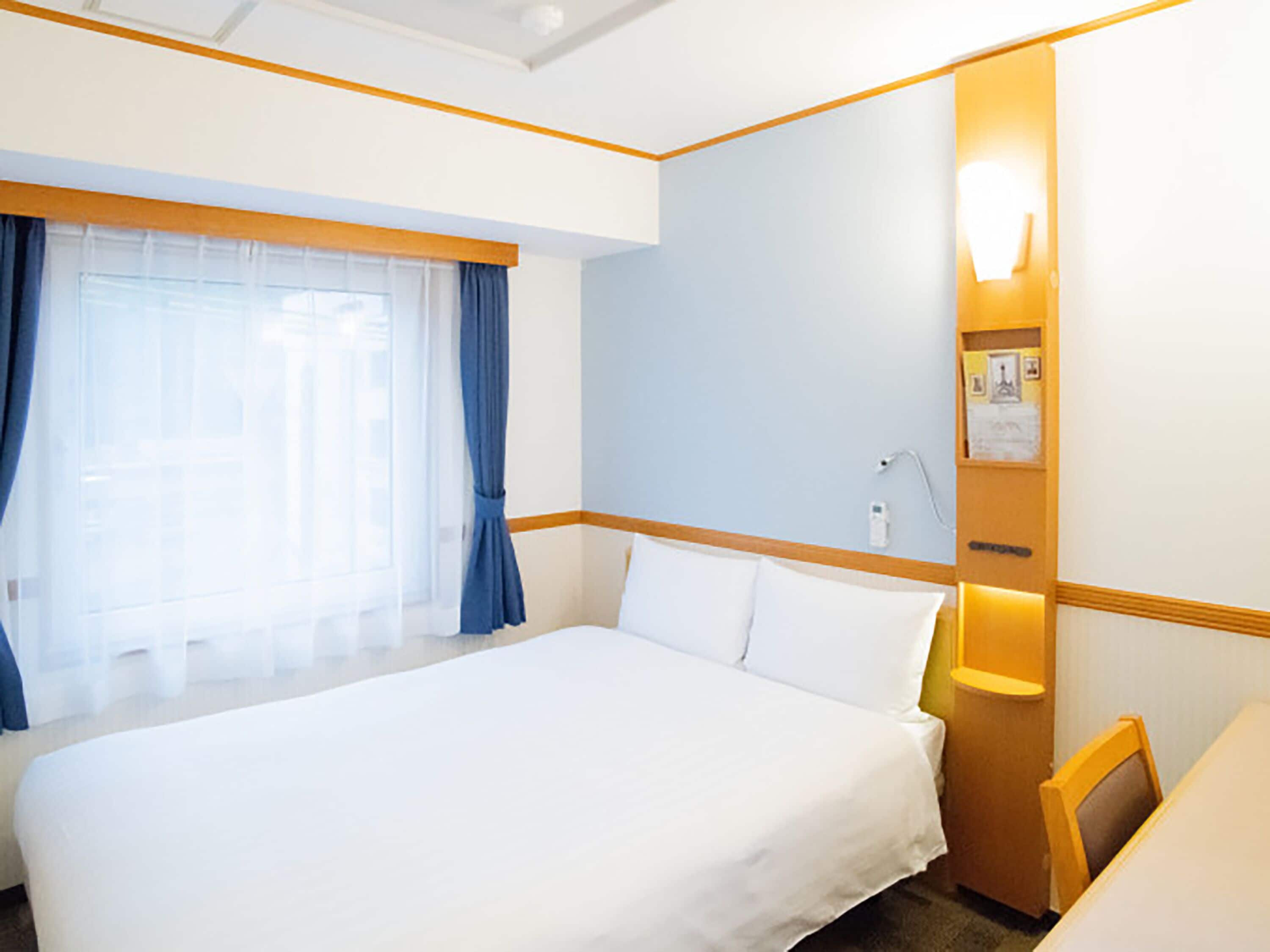 A hotel room with a large bed, a desk, and a window with curtains.