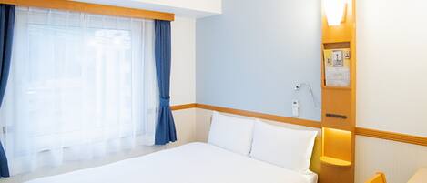 Una habitación de hotel con una cama grande, un escritorio y una ventana con cortinas.
