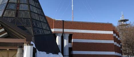 Un edificio con estructura piramidal de vidrio, fachada de ladrillo y un letrero en idioma extranjero.