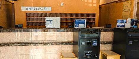 A reception area with a marble counter, a digital display, a security camera, and a vending machine.