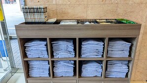 Una recepción de hotel con acabado de madera, con una pila de toallas dobladas en cada uno de los seis cajones inferiores.