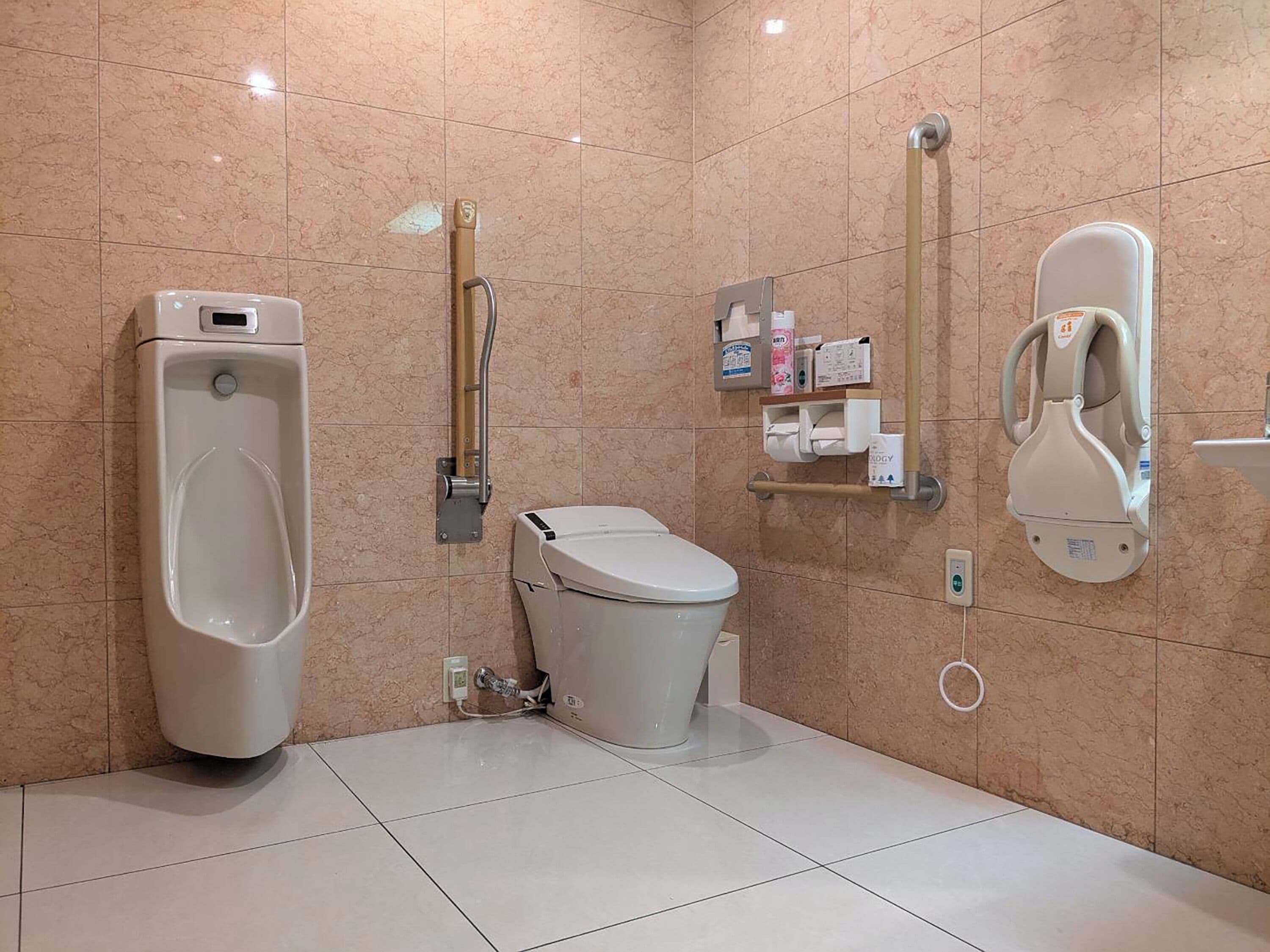 A modern bathroom with a urinal, toilet, and hand dryer.