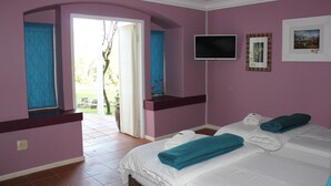 Une chambre avec deux lits, une télévision et une fenêtre donnant sur l’extérieur.