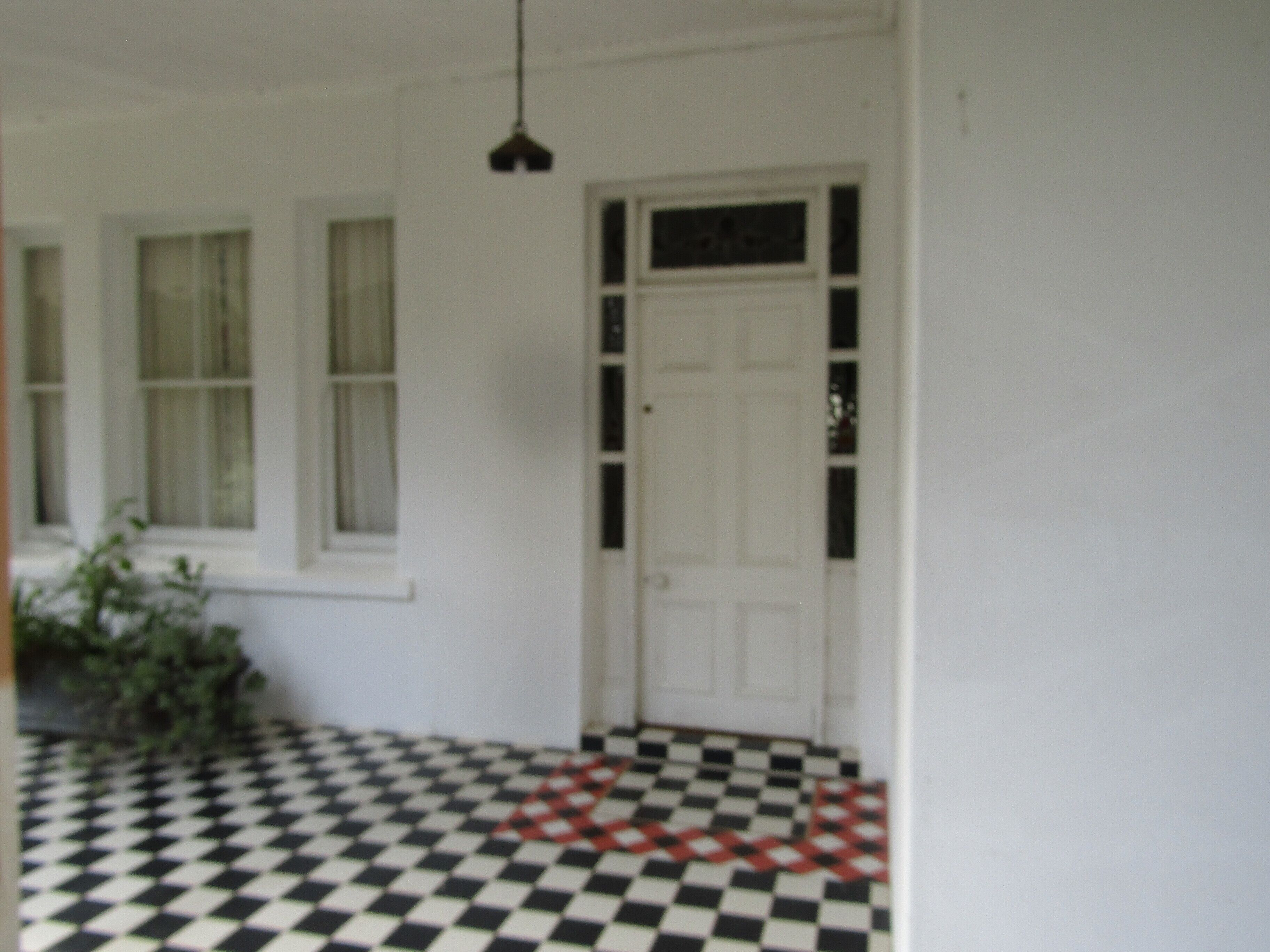 A room with a checkered floor, a white door, and a window with curtains.