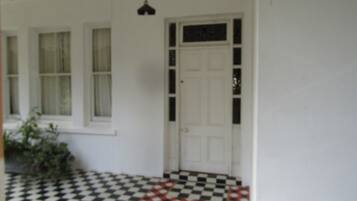 A room with a checkered floor, a white door, and a window with curtains.