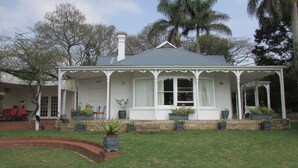Une maison dotée d’un porche abrité, d’un chemin en briques et de plantes en pot.