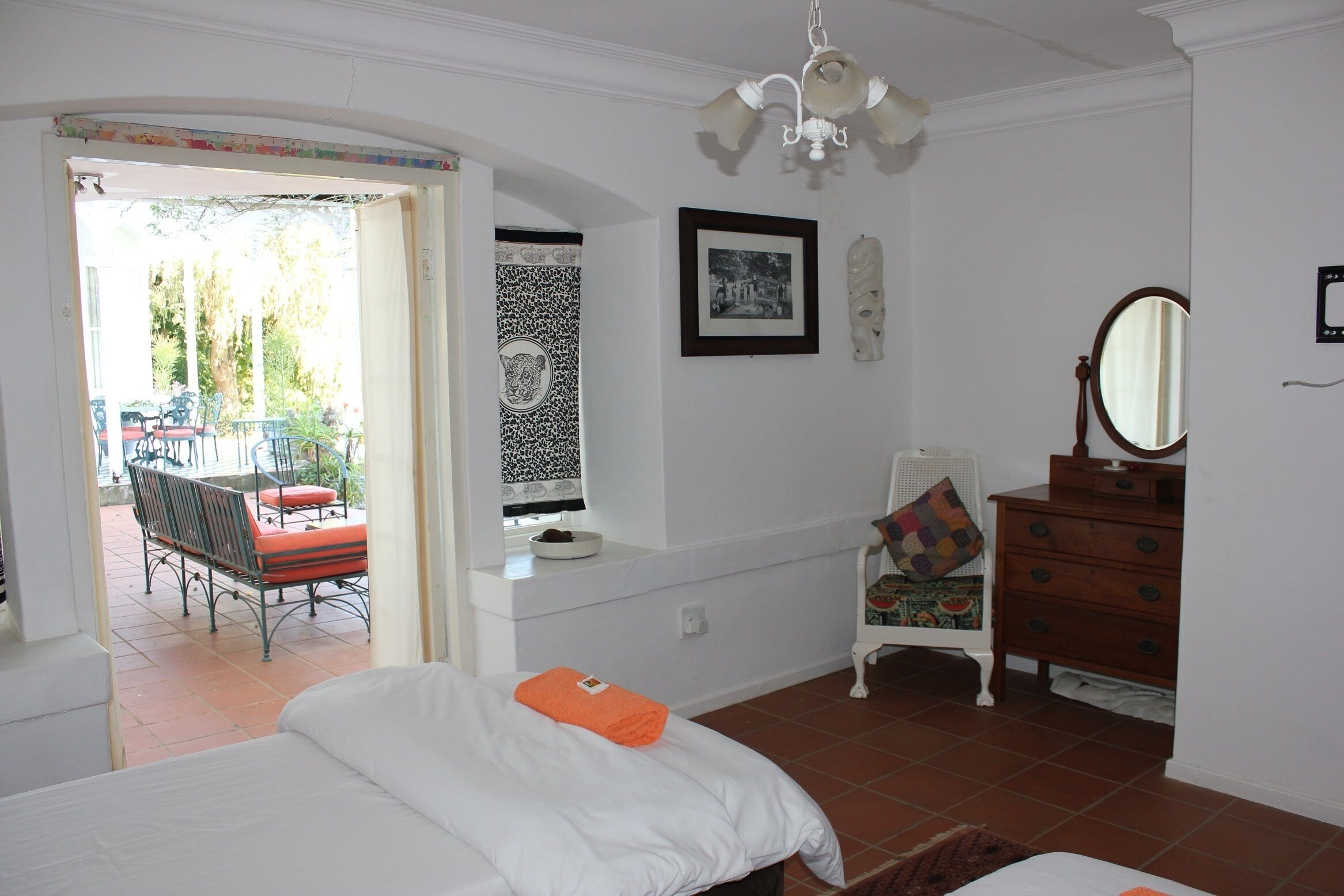A bedroom with a bed, dresser, and a chair. There is a window with a view of the outside.
