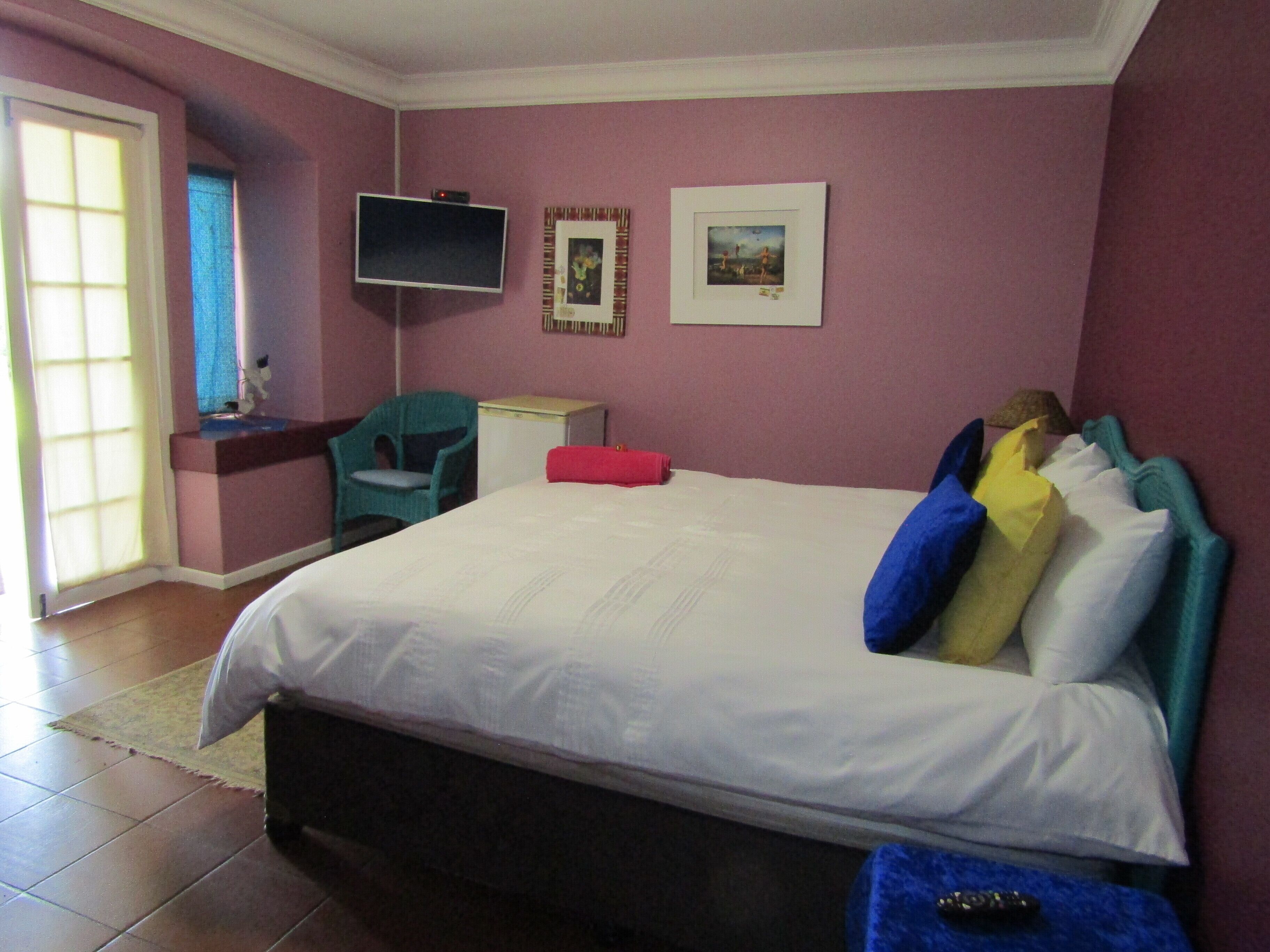 A bedroom with a bed, a TV, a chair, and a small table.
