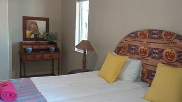 Hotelkamer met een bed, nachtkastje, lamp, raam en een wand met een gestreept hoofdeinde.