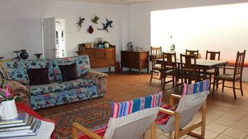 A living room with a sofa, chairs, a dining table, and a patterned rug.