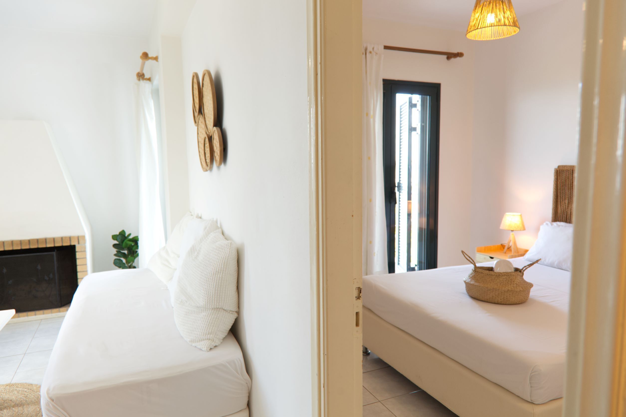 A hotel room with a bed, a bedside table with a lamp, a window with curtains, and a wall-mounted telephone.