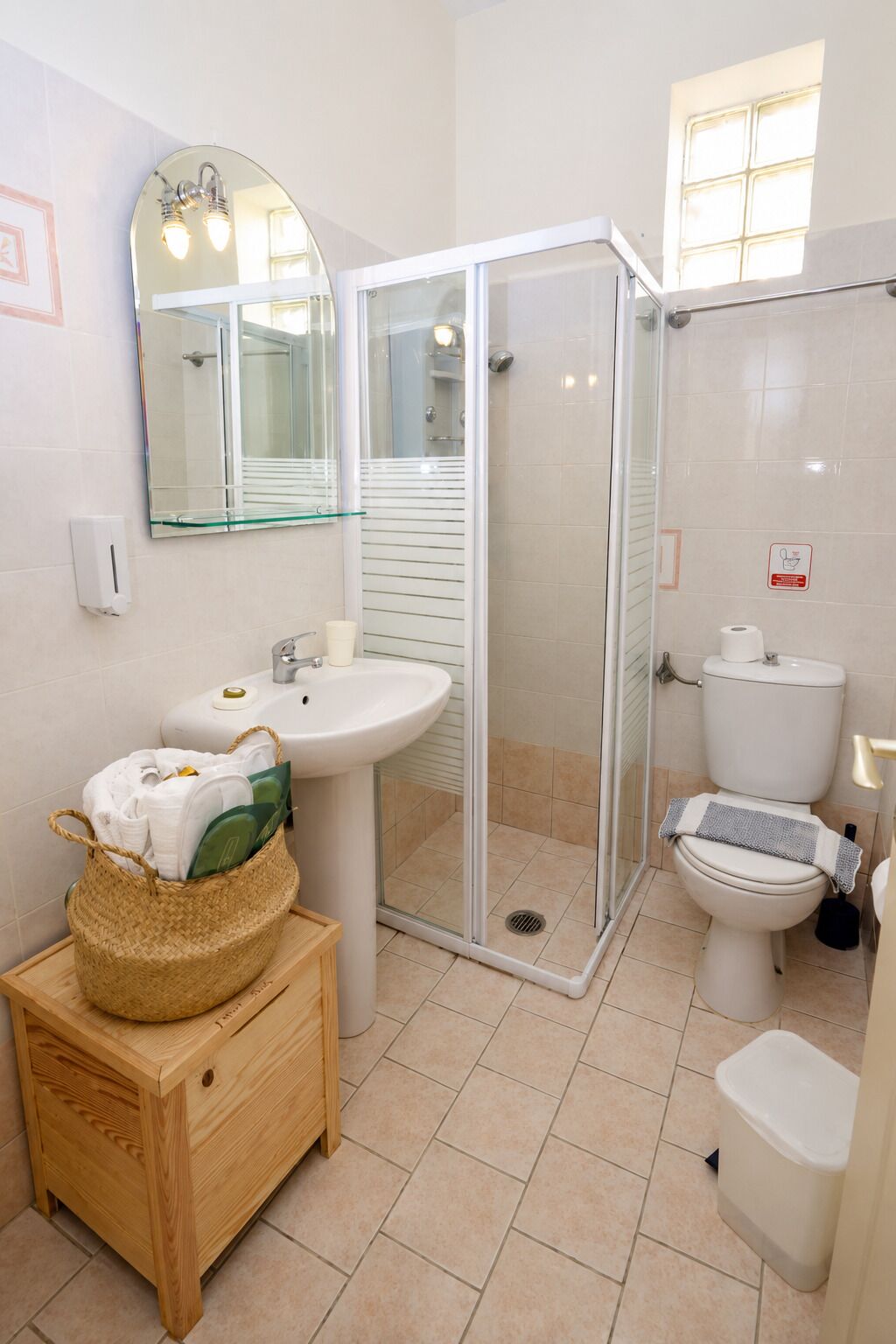 A modern bathroom with a glass shower enclosure, a sink, toilet, and a mirror.