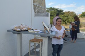 A table with food items and a person standing beside it. - Koukounari Apartments (Agistri)