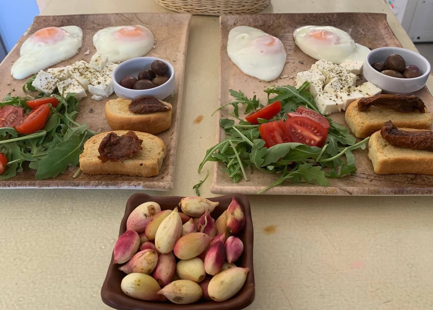 Dos tablas de madera con alimentos, como huevos, queso, tomates y verduras de hoja, y un cuenco de nueces.