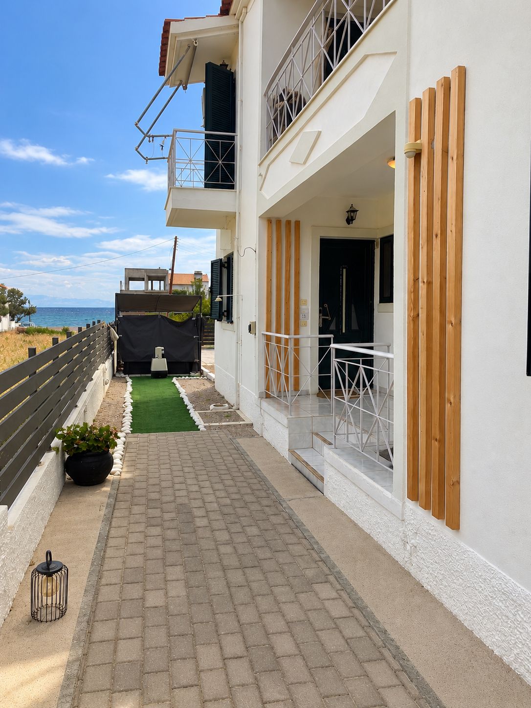 Un edificio con un camino empedrado, un balcón con barandilla y vista al mar.