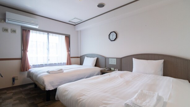 A hotel room with two beds, a clock on the wall, and an air conditioning unit. - Toyoko Inn Hokkaido Sapporo Susukino Minami (Sapporo)