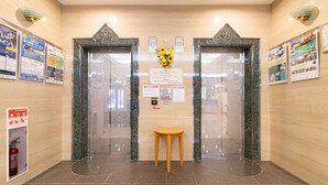 An elevator area with marble walls, a wooden stool, and informational posters. - Toyoko Inn Hokkaido Sapporo Susukino Minami (Sapporo)