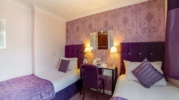 Habitación de hotel con dos camas, un escritorio y una silla.