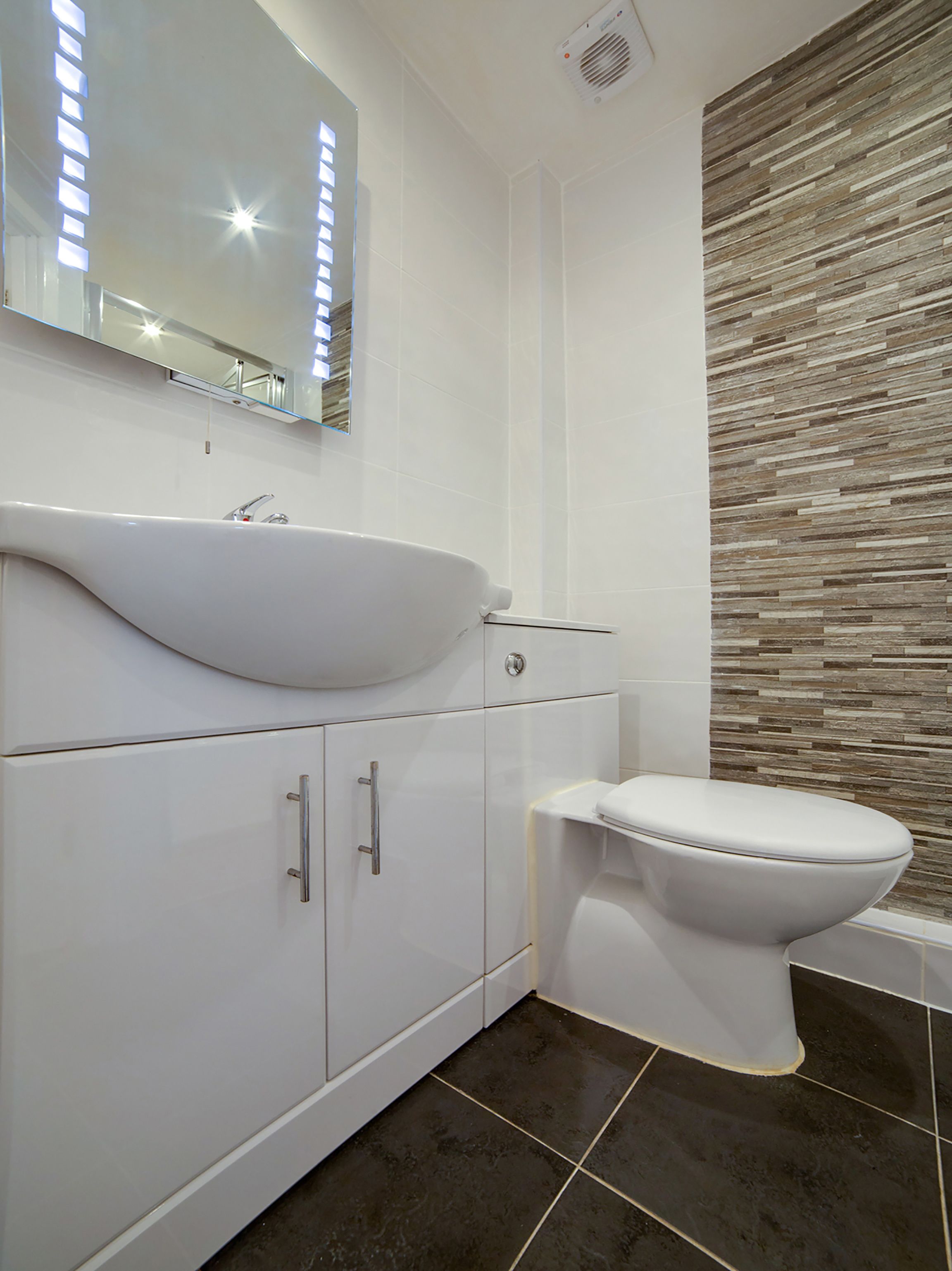 Un bagno moderno con lavandino, specchio e servizi igienici bianchi.