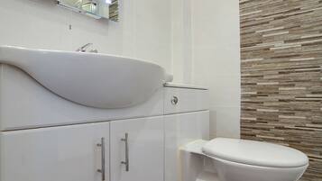 Un bagno moderno con lavandino, specchio e servizi igienici bianchi.