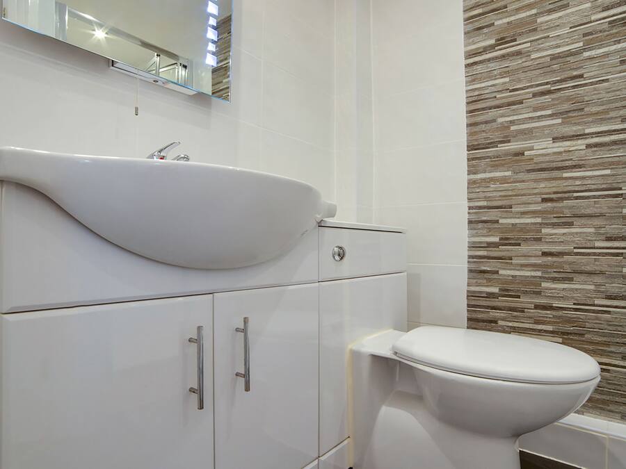 Un bagno moderno con lavandino, specchio e servizi igienici bianchi.