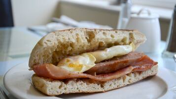 Un panino con uova e prosciutto su un piatto bianco.