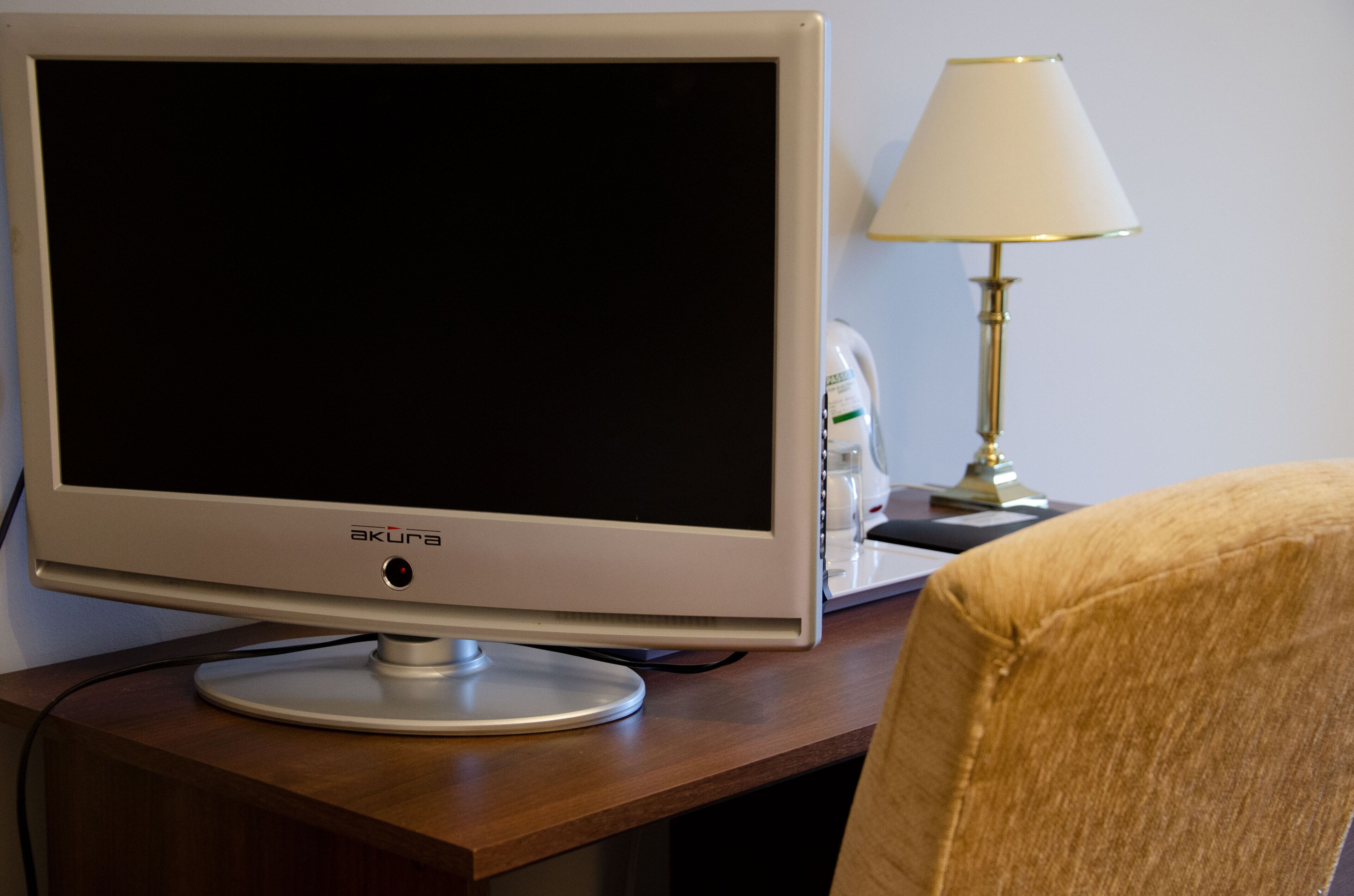 Un écran plat, une lampe et une chaise sur un bureau en bois.