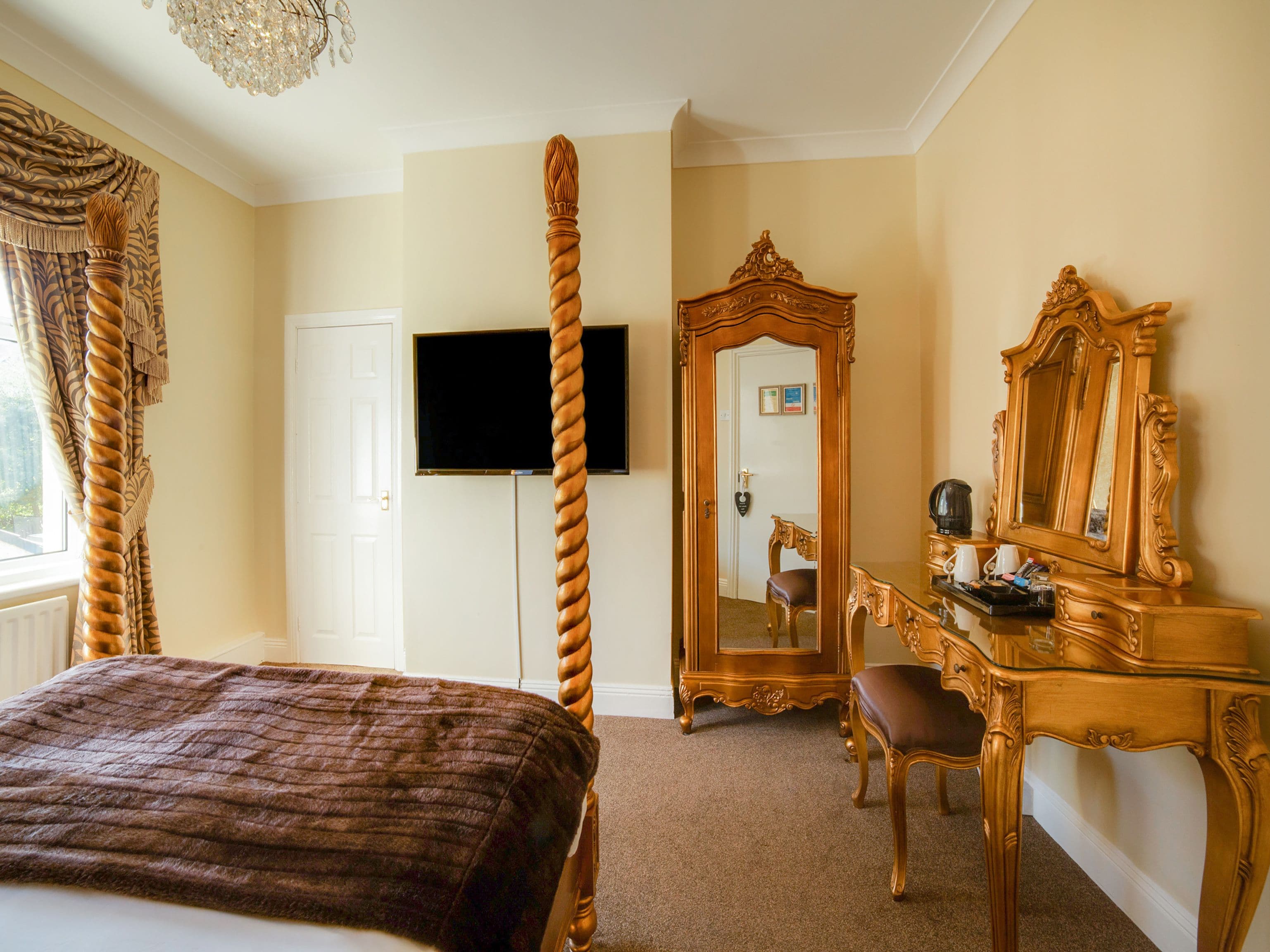 A hotel room with a large bed, a television, a mirror, and a wooden dresser.