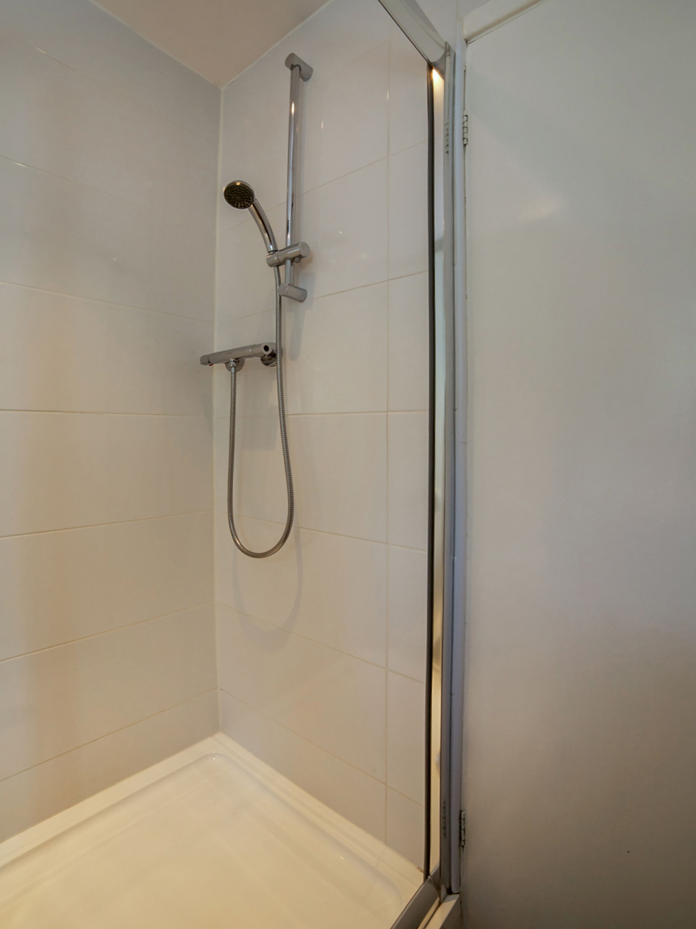 Een douche met een handdouche en een apart handmatige douchestraal.