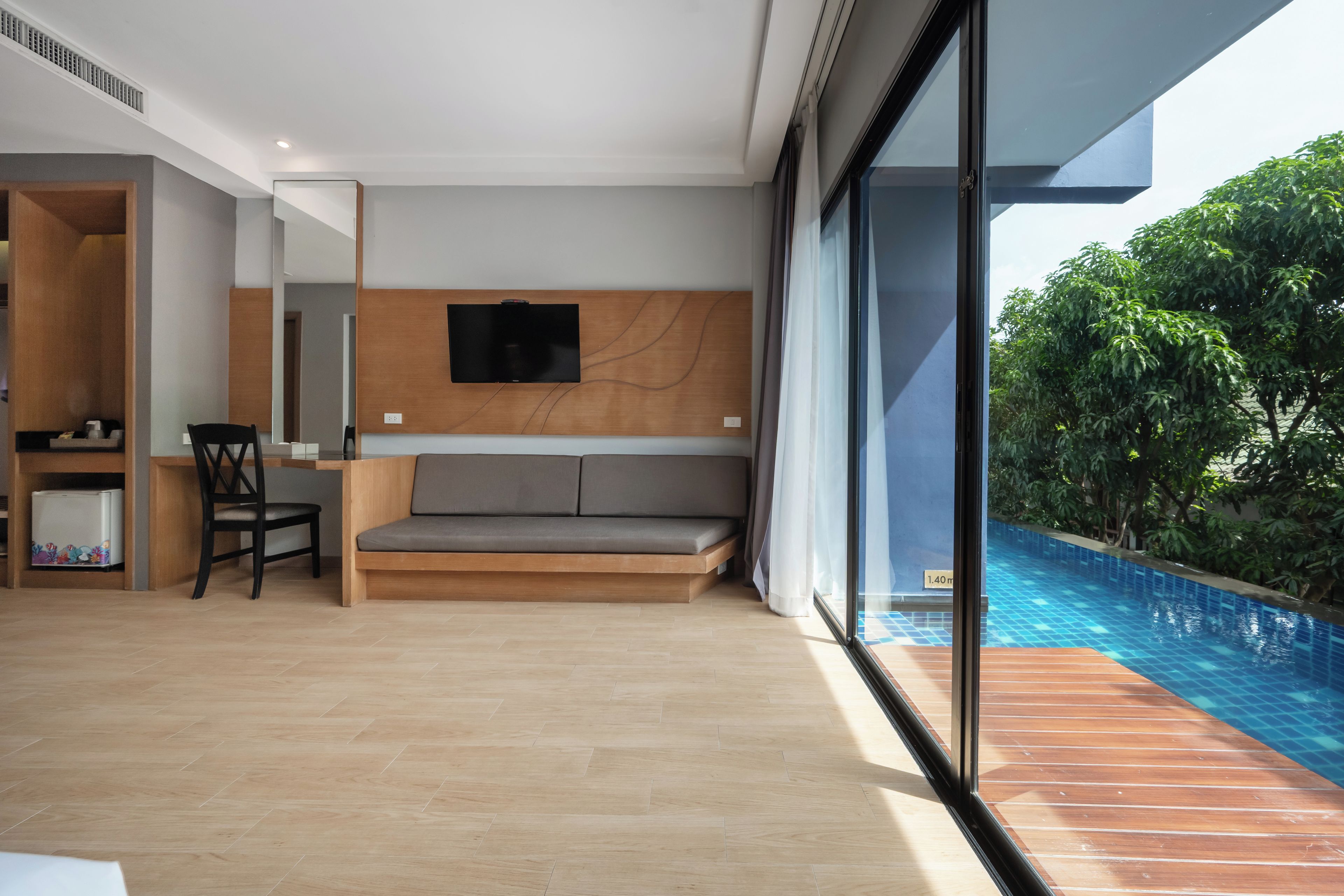 A modern living room with a sofa, a television, and a dining area with chairs and a table.