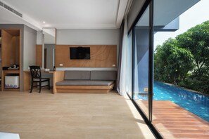 A modern living room with a sofa, a television, and a dining area with chairs and a table.