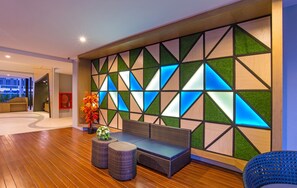 A modern lobby with a geometric wall design, a seating area with a sofa and two side tables, and a potted plant. - Ava Sea Krabi Resort (Krabi)