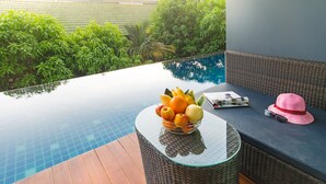 A poolside area with a glass table holding a fruit bowl, sunglasses, and a hat. - Ava Sea Krabi Resort (Krabi)