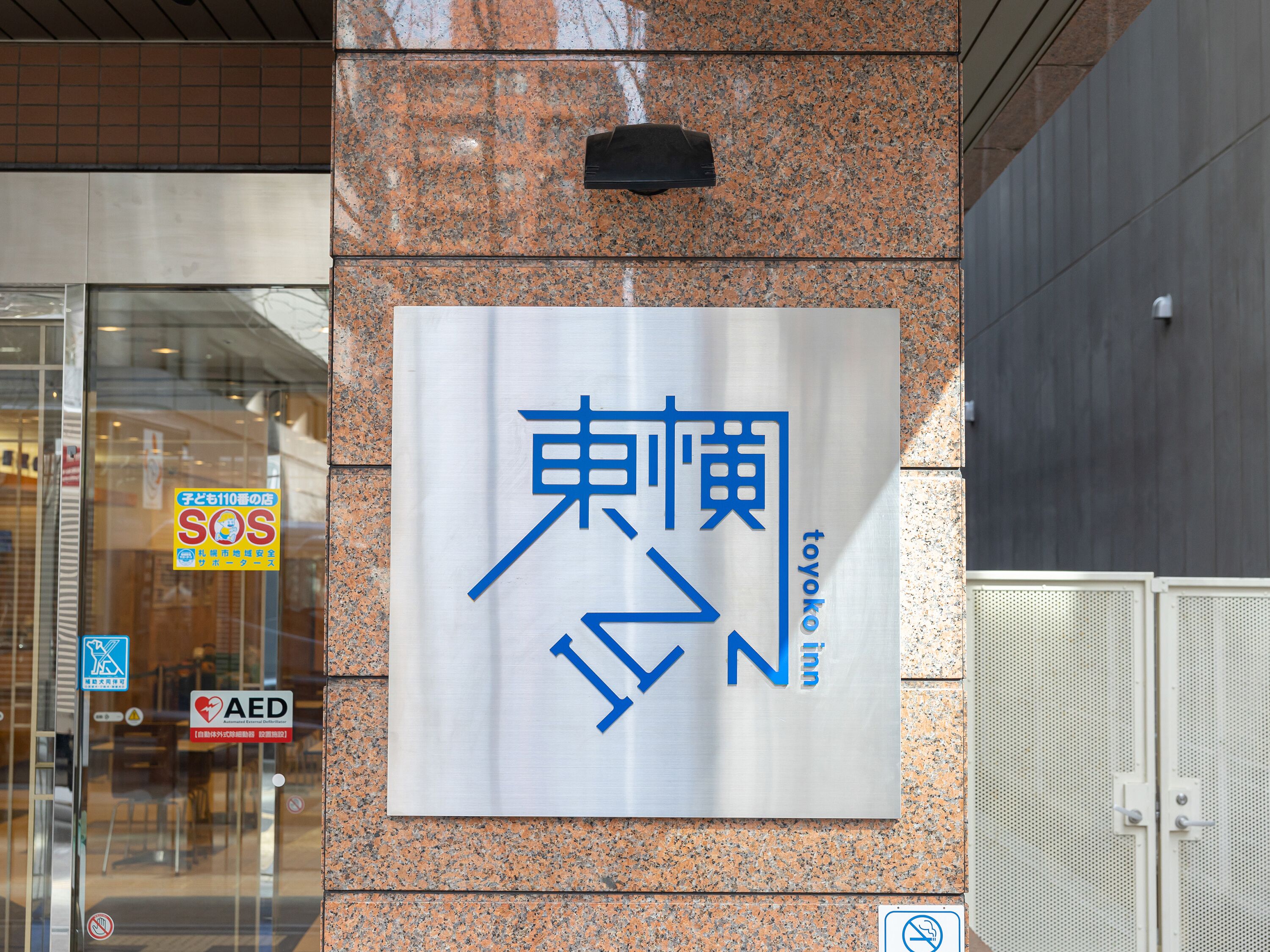 Ein Schild mit japanischen Schriftzeichen und dem Wort 'Toyoko' an der Gebäudefassade.