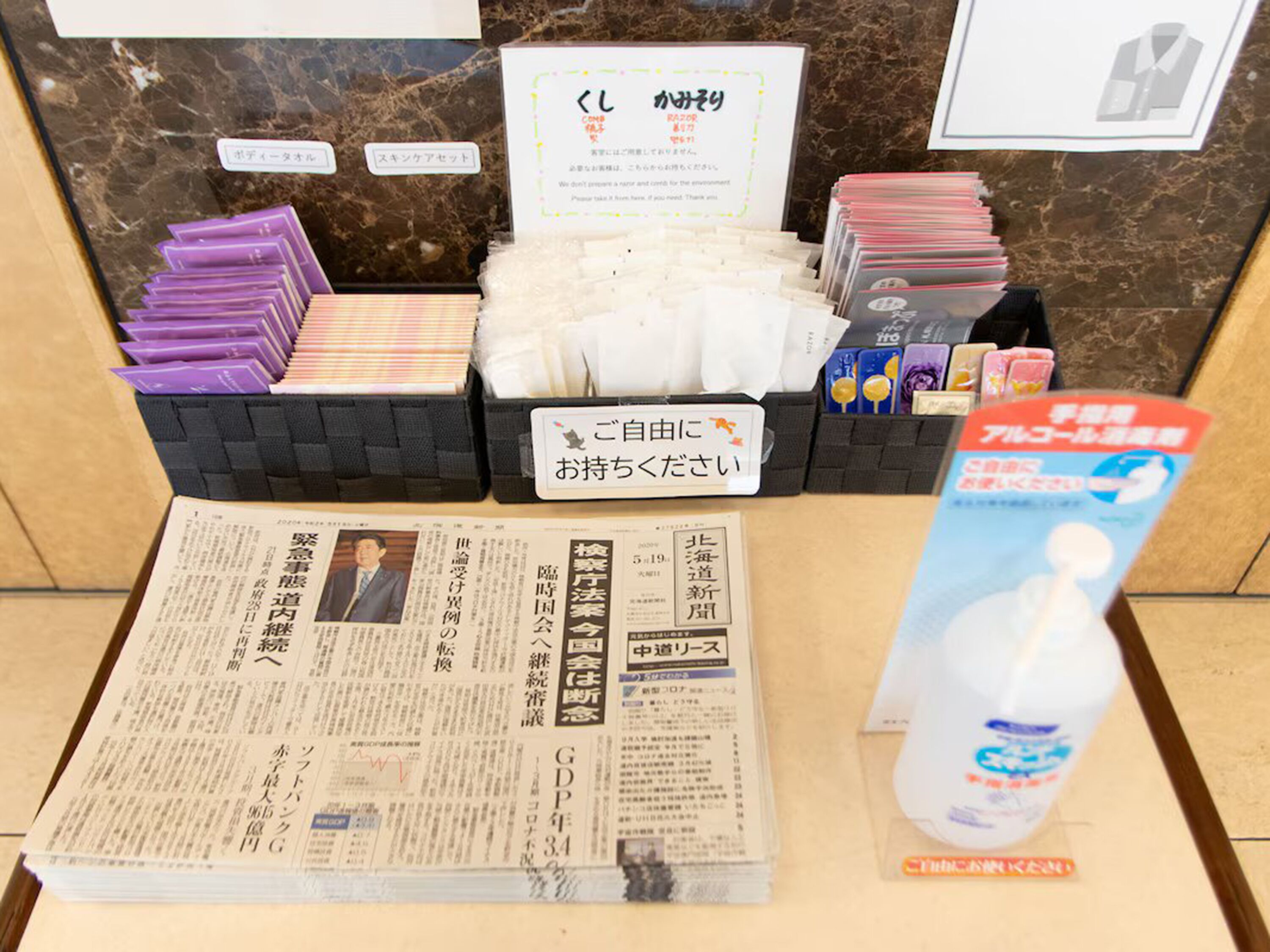 Een receptiebalie met een krant, tijdschriften en een fles handdesinfectiemiddel.