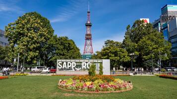 A park with a prominent tower, a sign reading "SAPPORO," and a flower bed.