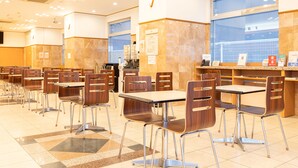 Una cafetería con varias mesas y sillas, una máquina de café y un tablero de menú.