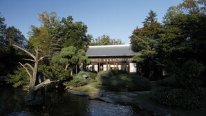 Un edificio japonés tradicional con un estanque en primer plano.