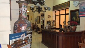 A lobby with a reception desk, a large decorative vase, and various wall decorations. - Mandala Puri Malang (Malang)