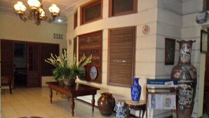 A room with a dining table, chairs, a potted plant, a vase, and a decorative sculpture. - Mandala Puri Malang (Malang)