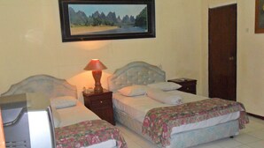 A bedroom with two beds, a nightstand with a lamp, a television, and a framed picture on the wall. - Mandala Puri Malang (Malang)