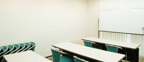 A conference room with a whiteboard, teal chairs, and a carpeted floor.