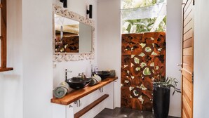 A bathroom with a wooden vanity, a large mirror, and a potted plant. - Villa LeoNora (Ubud)