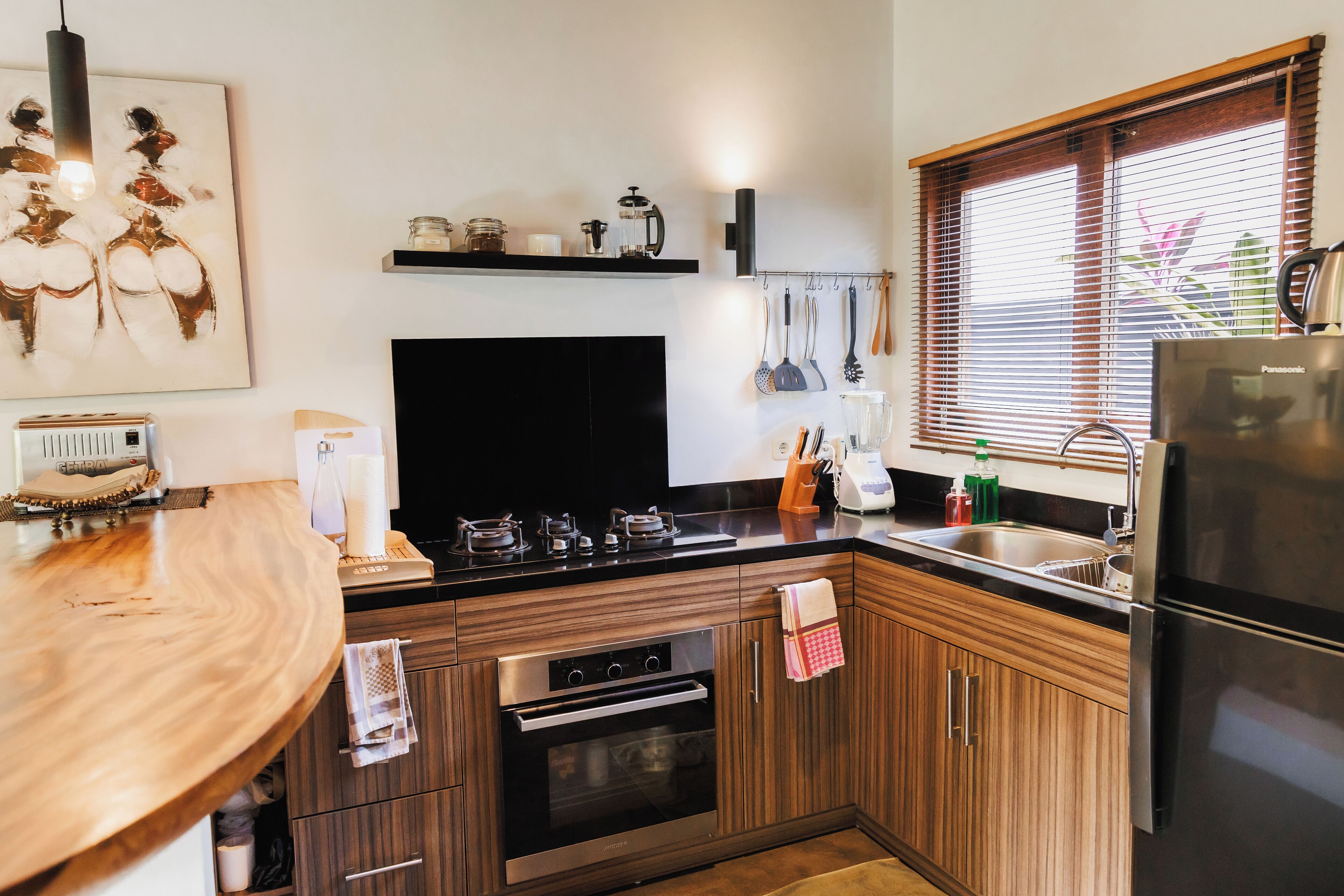 Une cuisine moderne avec des meubles en bois, un réfrigérateur en acier inoxydable et un four noir.