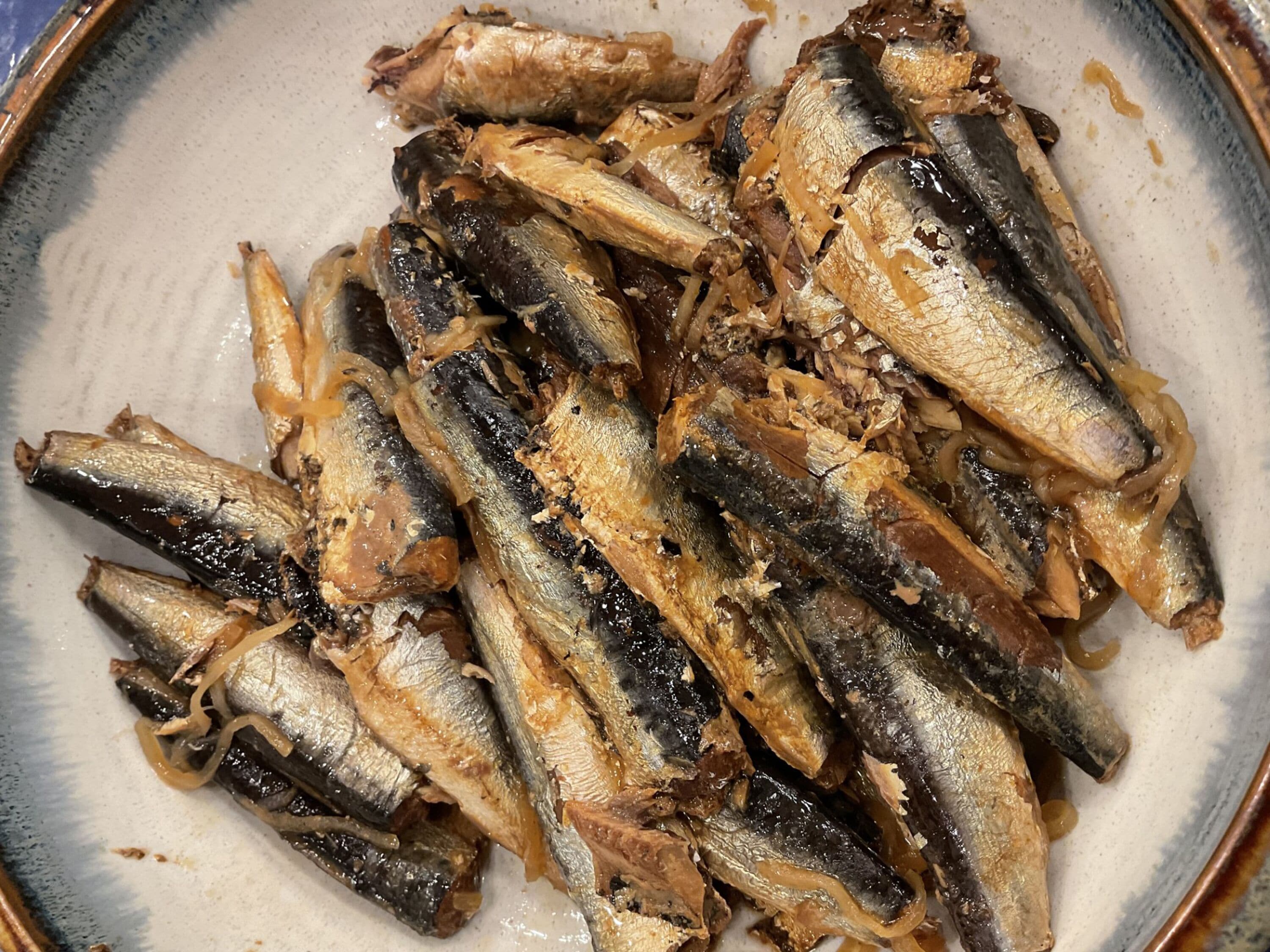 A plate of cooked fish with onions.